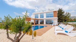 A modern villa with a swimming pool, lounge chairs, and a view of the sea. - Coral Elite Residence 12. New luxury villa with private pool and hot tub jacuzzi (Paphos)