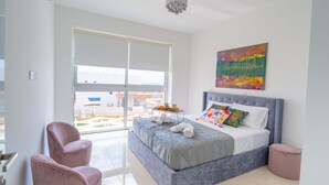 A modern bedroom with a large bed, a grey headboard, and a colorful abstract painting above it. - Coral Elite Residence 12. New luxury villa with private pool and hot tub jacuzzi (Paphos)