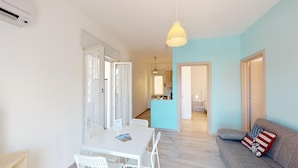 A modern apartment with a dining area, a living room with a sofa and a decorative pillow, and a kitchen visible in the background. - ~ Playa Houses ~ With Wonderful Sea View, Parking. (Balestrate)