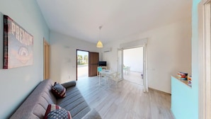 A modern living room with a sofa, a dining table, and a kitchen area visible through an open door. - ~ Playa Houses ~ With Wonderful Sea View, Parking. (Balestrate)