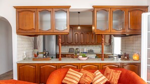 A kitchen with wooden cabinets, a countertop, and a red sofa with striped pillows.