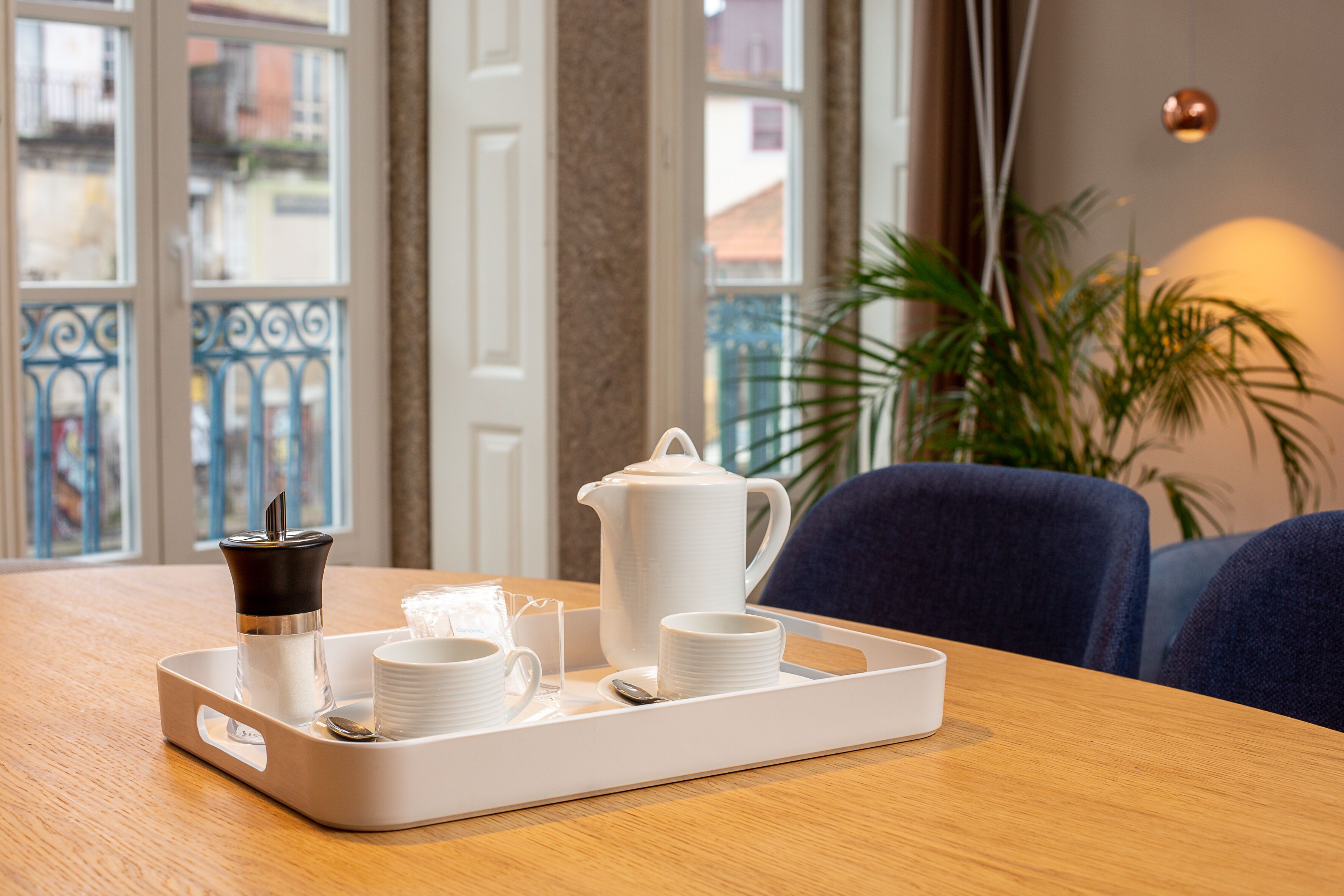 A tray with a coffee pot, cups, and a sugar container on a wooden table.