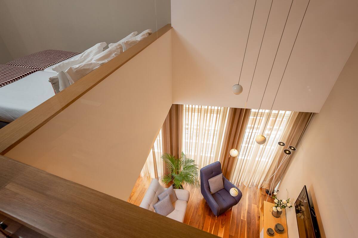 Un salon moderne avec un plancher en bois, un canapé, un fauteuil et une plante en pot.