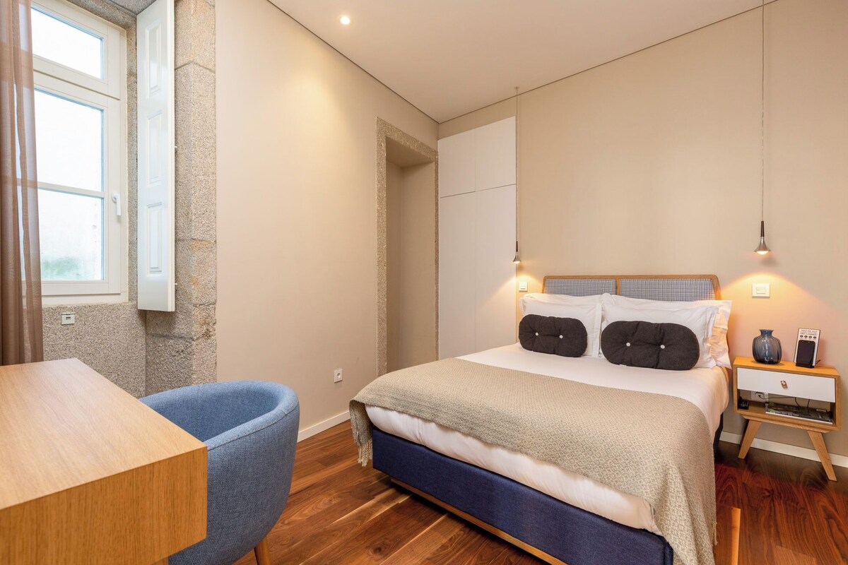 A modern bedroom with a bed, bedside table, and a chair.