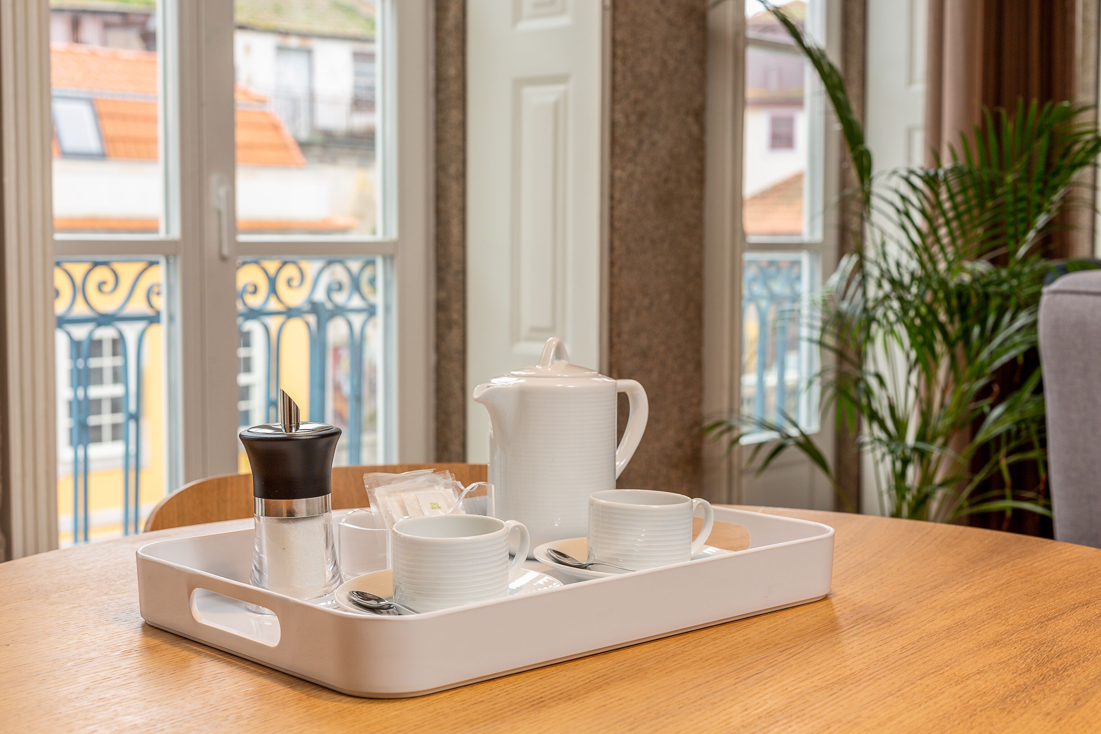 Un plateau avec une théière, des tasses et un sucrier, posé sur une table en bois.