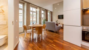 A modern kitchen with a built-in oven, a dining area with a round table and chairs, and large windows with curtains. - RS Porto Historic Center (Porto)