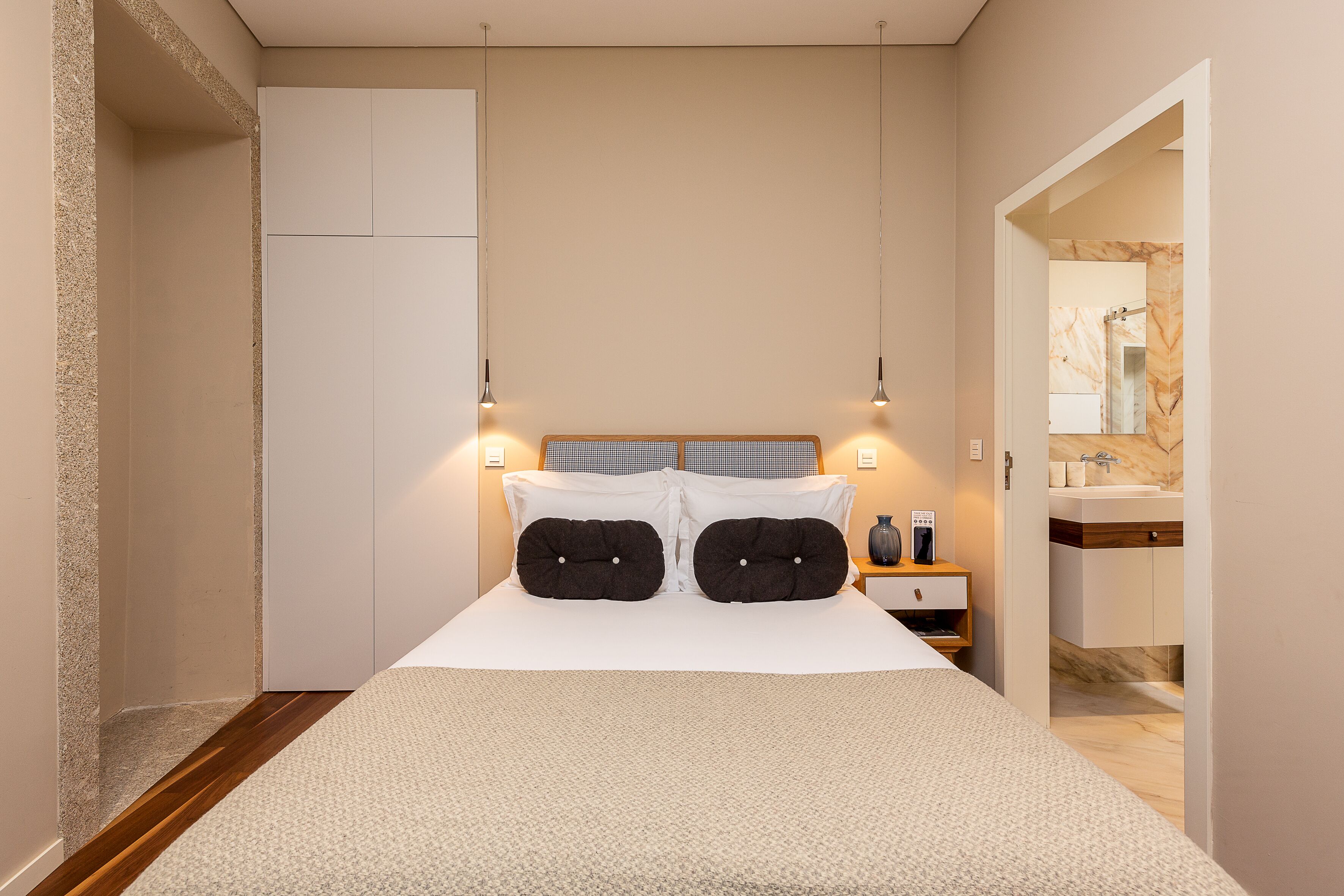 A bedroom with a bed, bedside tables, and a view into a bathroom.