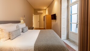 A hotel room with a large bed, a flat-screen TV mounted on the wall, and a window with curtains. - RS Porto Historic Center (Porto)