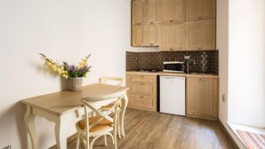 A small kitchen with wooden cabinets, a microwave, and a dishwasher. There is a table with chairs and a vase of flowers.