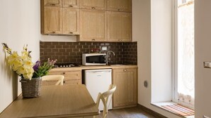 A compact kitchen with wooden cabinets, a microwave, and a dishwasher.