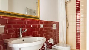 A bathroom with a white sink, toilet, and bidet, red tiled walls, and a shower curtain.