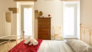A bedroom with a bed, wooden dresser, chair, and a mirror.