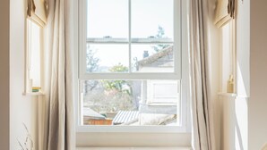 Une chambre dotée d’une grande fenêtre, d’un lit, d’une petite table avec des éléments pour le petit-déjeuner et d’un radiateur.