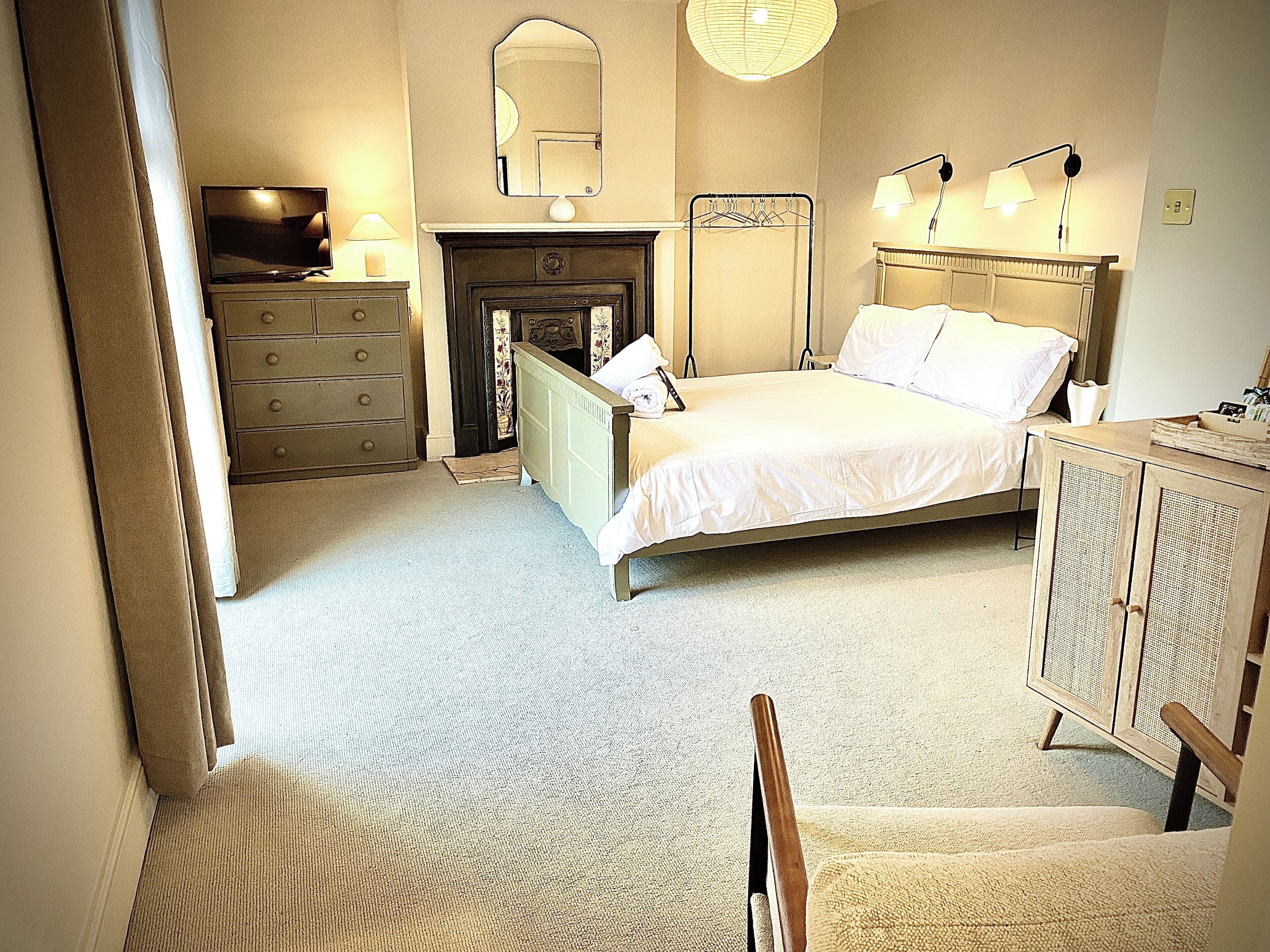 Une chambre à coucher avec un lit, une commode, un miroir et une cheminée.