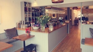 Un espace bar moderne avec un comptoir en bois, des étagères remplies de bouteilles et un coin salon comprenant un banc et une table.