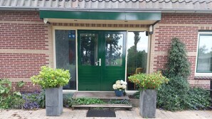 Un edificio de ladrillo con una puerta verde y dos macetas con plantas a cada lado de la entrada.