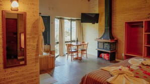 A cozy room with a wooden ceiling, a fireplace, a dining area with a table and chairs, and a large mirror on the wall. - Terrazzo dos Alpes (Camanducaia)