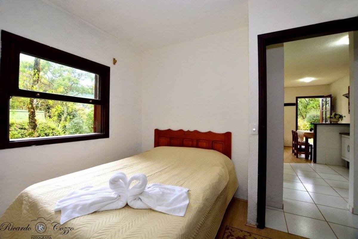 Ein Schlafzimmer mit einem Bett, einem Fenster und Blick auf Grünfläche.