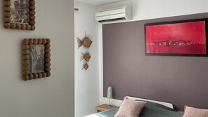 A bedroom with a bed, a red abstract painting, and wall-mounted decor. - PORTO VECCHIO CALA ROSSA - BEAUTIFUL AIR-CONDITIONED APARTMENT 800M FROM THE BEACH (Lecci)