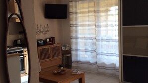 A living room with a wooden coffee table, a TV mounted on the wall, and a striped curtain. - PORTO VECCHIO CALA ROSSA - BEAUTIFUL AIR-CONDITIONED APARTMENT 800M FROM THE BEACH (Lecci)