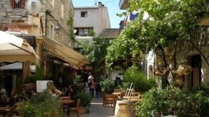 A narrow street with outdoor seating, stone buildings, and greenery. - PORTO VECCHIO CALA ROSSA - BEAUTIFUL AIR-CONDITIONED APARTMENT 800M FROM THE BEACH (Lecci)