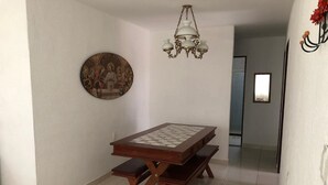 A dining area with a wooden table and benches, a chandelier, and a wall-mounted painting. - Casa Grande Gravata (Gravata)