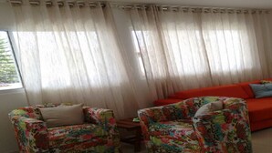 A living room with two colorful armchairs, a red sofa, and sheer curtains. - Casa Grande Gravata (Gravata)