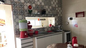 A kitchen with patterned tiles, a red coffee machine, a stove, and a dining table with chairs. - Casa Grande Gravata (Gravata)
