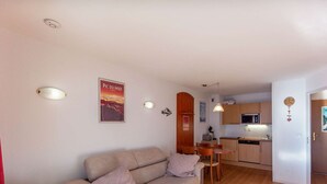 A compact living space with a sofa, a small wooden table, a kitchenette, and a dining area. - Pleasant T2, parking - 4 guests (La Mongie)