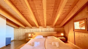 Un dormitorio de cabaña de madera con una cama, dos mesitas de noche y una ventana.