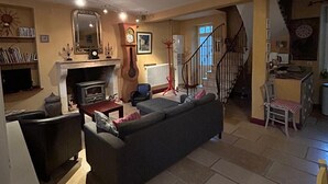 Ein gemütliches Wohnzimmer mit Kamin, einer Couch, einem Fernseher und einer Treppe zu einem anderen Raum.