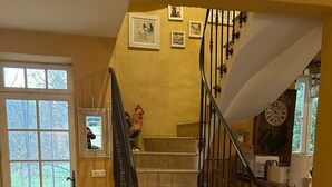 Eine Treppe mit schwarzer Geländer, ein gelber Stuhl und ein gerahmtes Bild an der Wand.