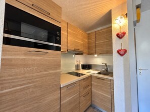 A modern kitchen with wooden cabinets, a black oven, and a sink.