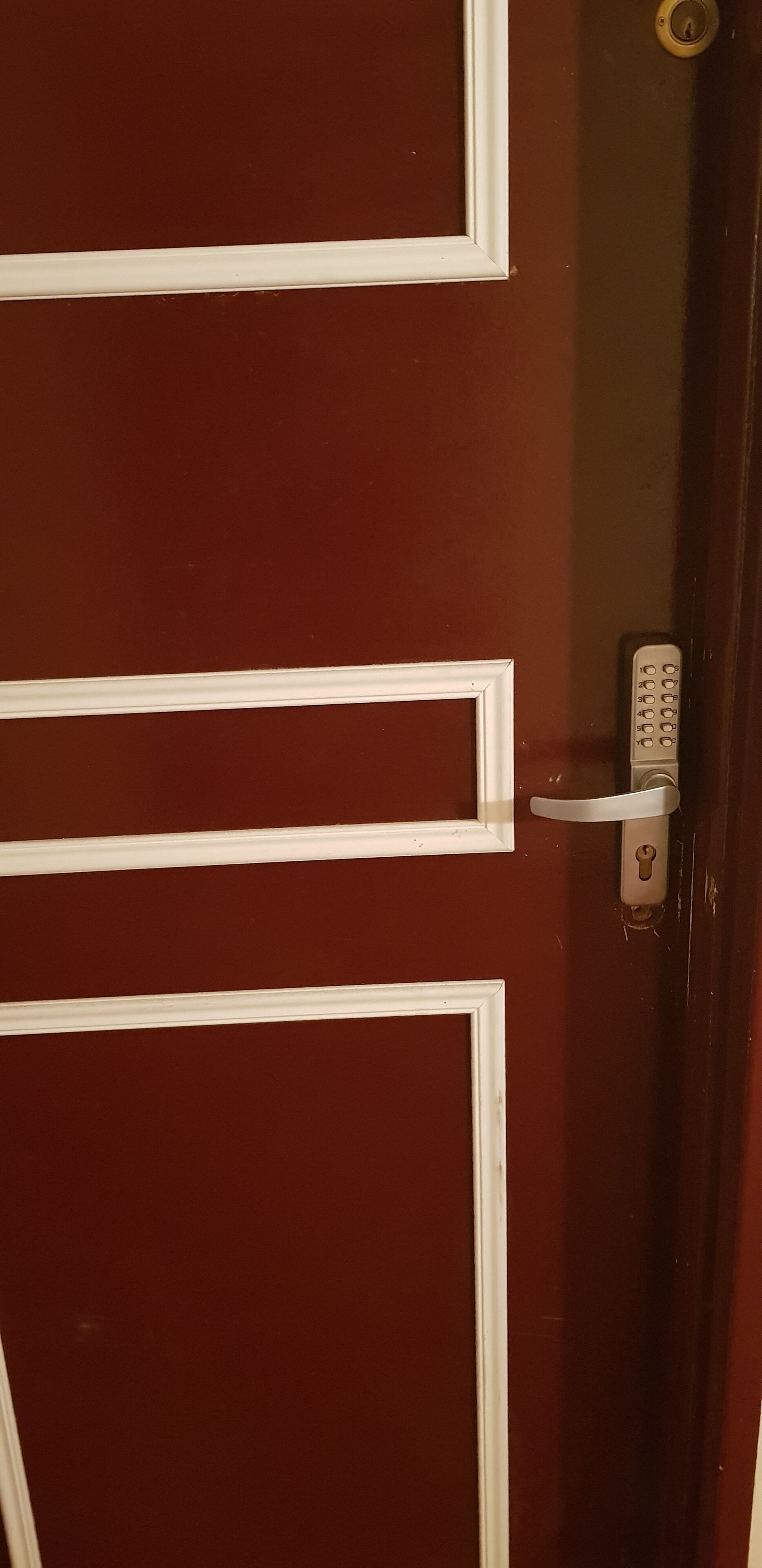 Puerta roja con detalles blancos y un teclado electrónico.