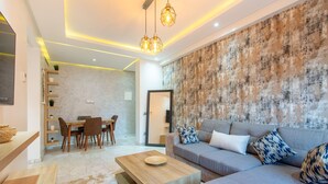 Una sala de estar moderna con un sofá gris, una mesa de centro de madera y un comedor con una mesa y sillas de madera.