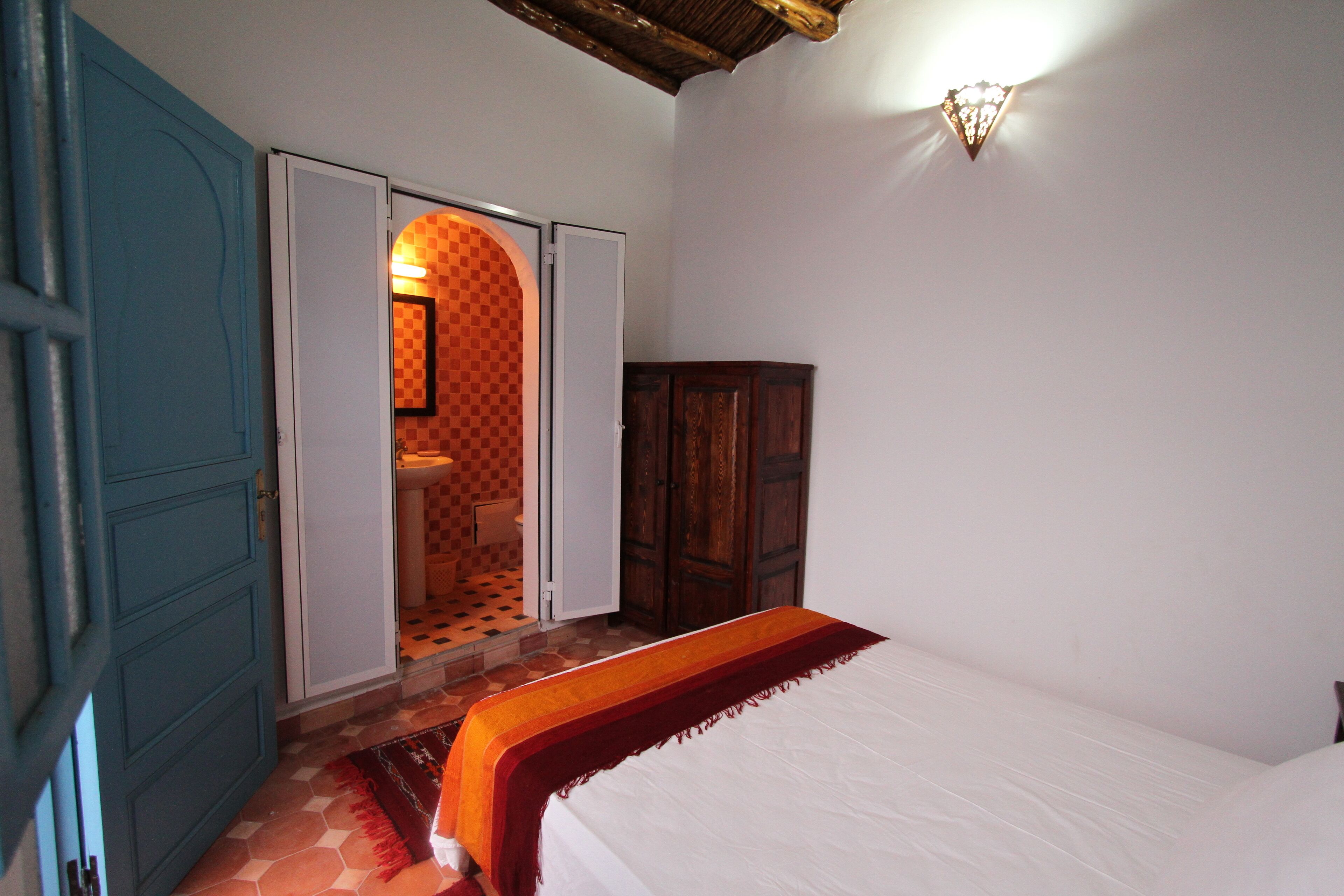 A bedroom with a bed, a wardrobe, and a bathroom visible through an open door.