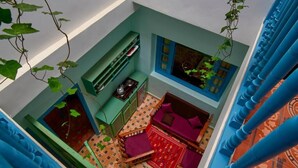 Quarto pequeno com cama, uma mesa e janela.