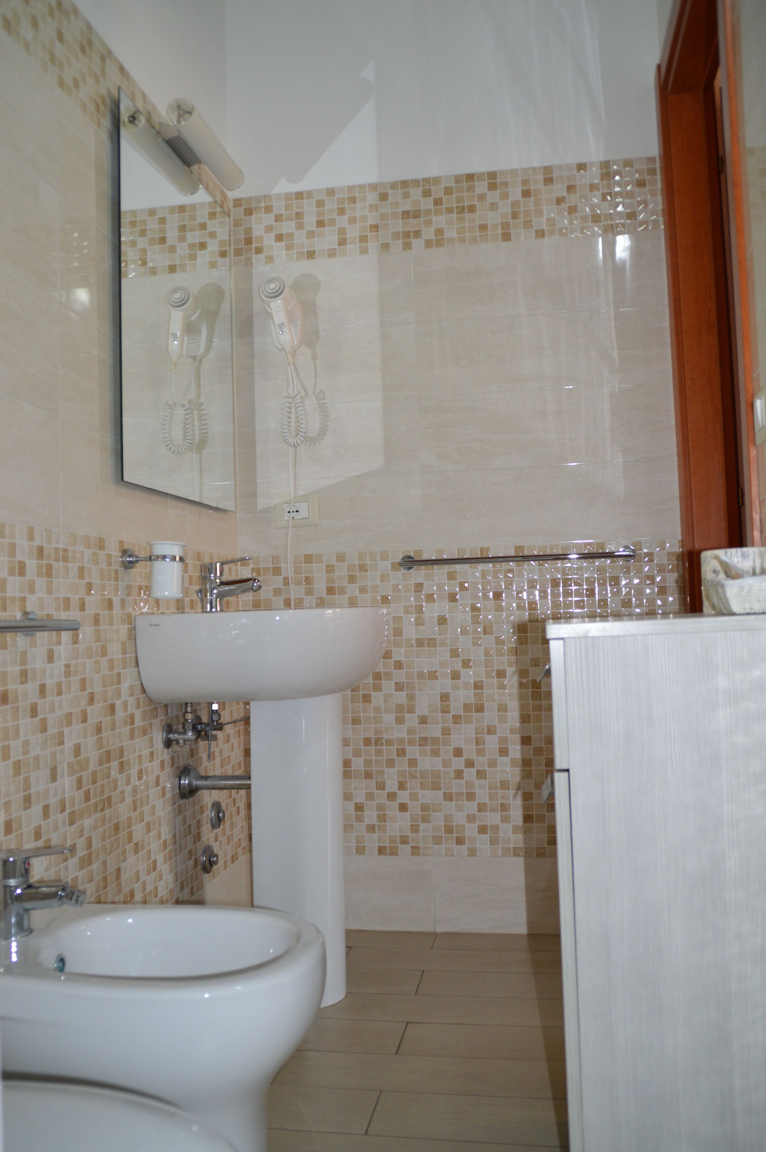 A bathroom with a sink, bidet, and a mirror.