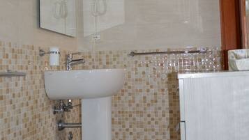 A bathroom with a sink, bidet, and a mirror.