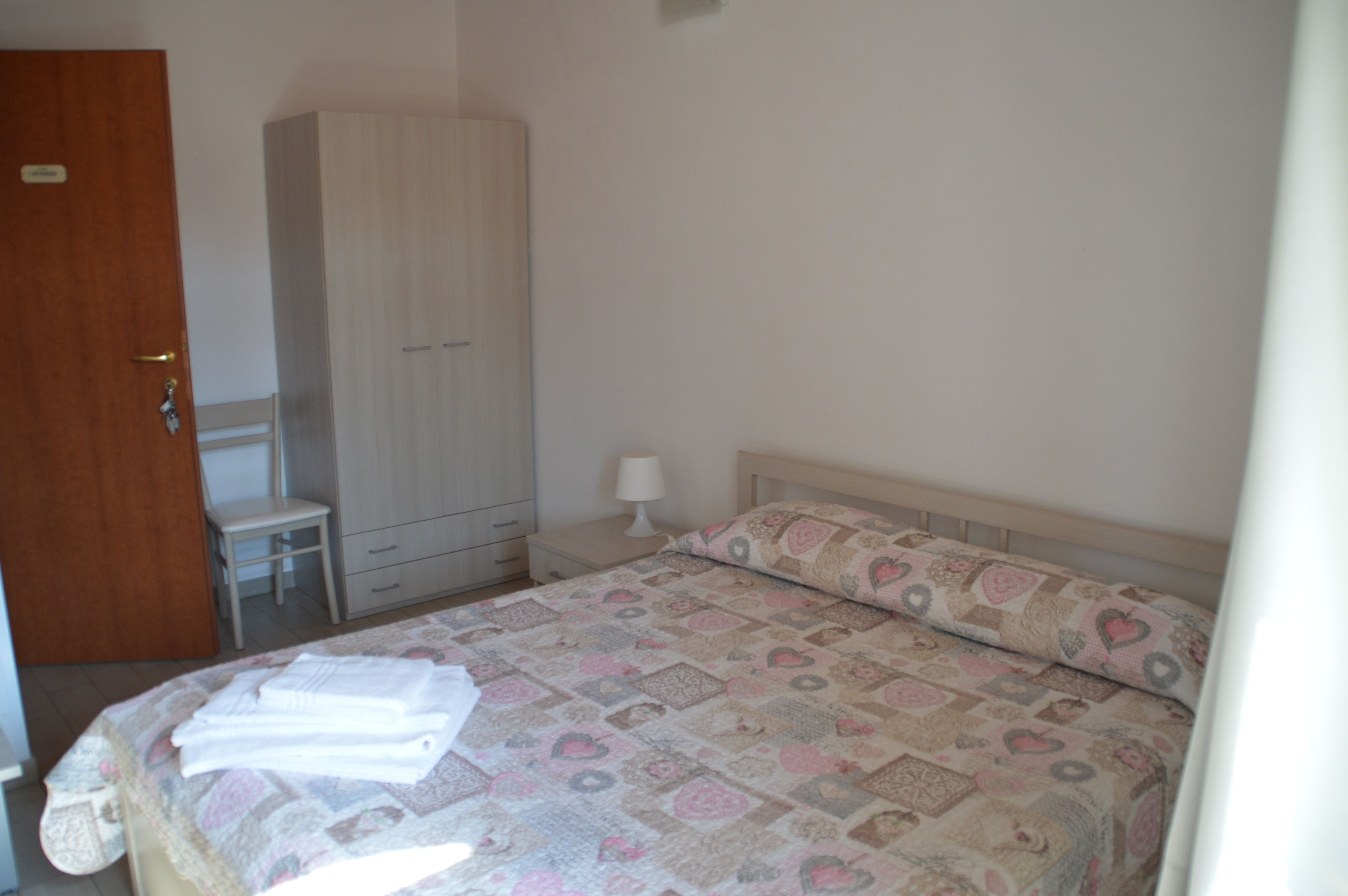 Un dormitorio con una cama, un armario, una mesita de noche y una silla.