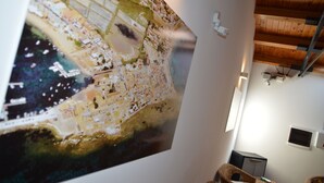 A large map of a coastal town with a wooden ceiling and a wall-mounted light fixture. - Il Veliero (Pachino)