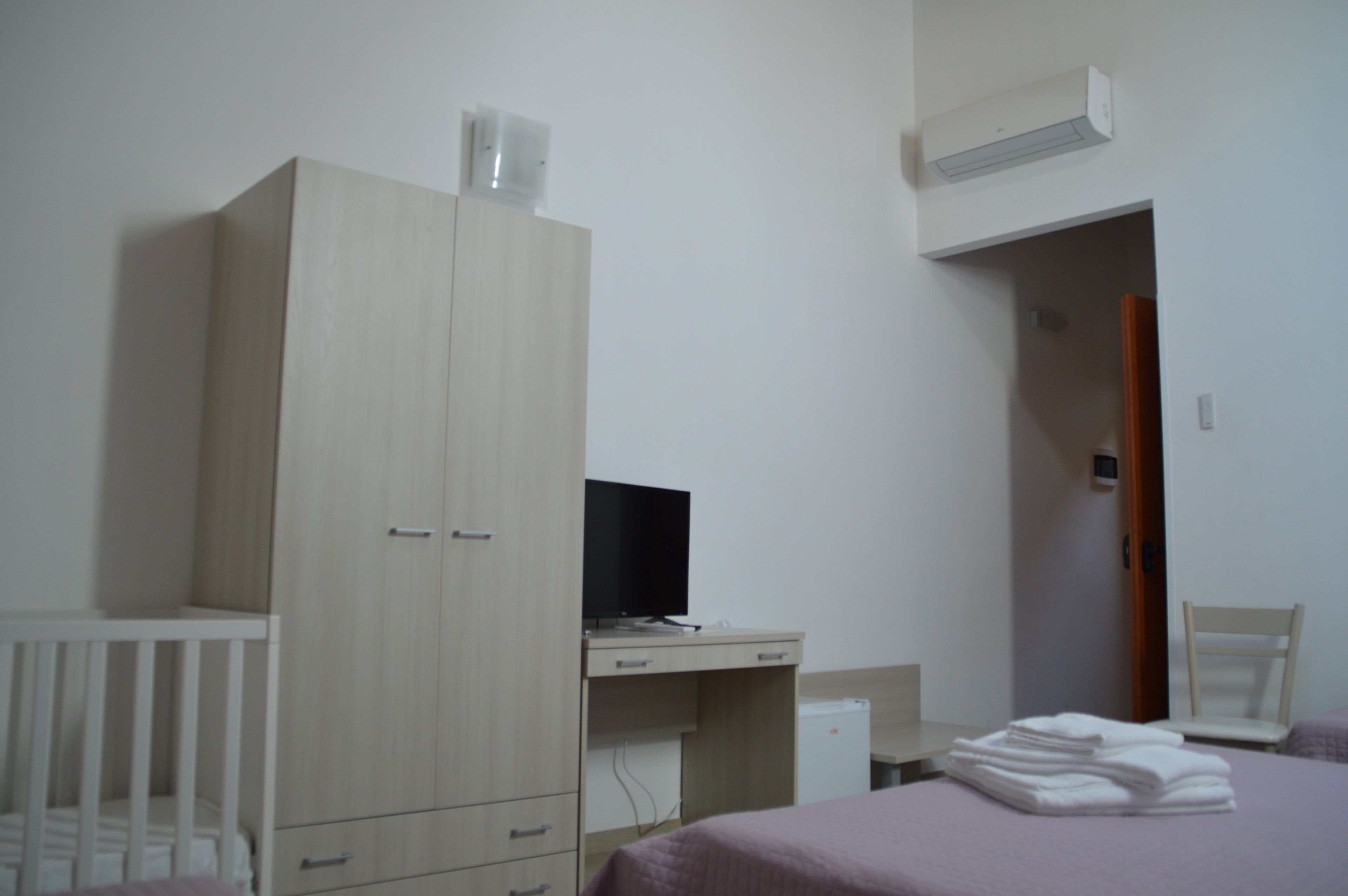 Quarto com cama, escrivaninha, guarda-roupa e ar condicionado.