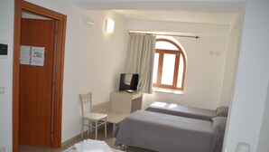A hotel room with two beds, a desk with a TV, a chair, and a window with curtains. - Il Veliero (Pachino)