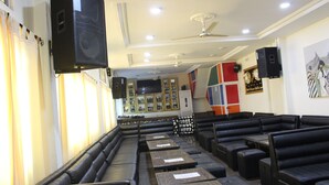 A restaurant with black leather booths, tables, and ceiling fans. - Hôtel la Tour d'Argent (Garoua)