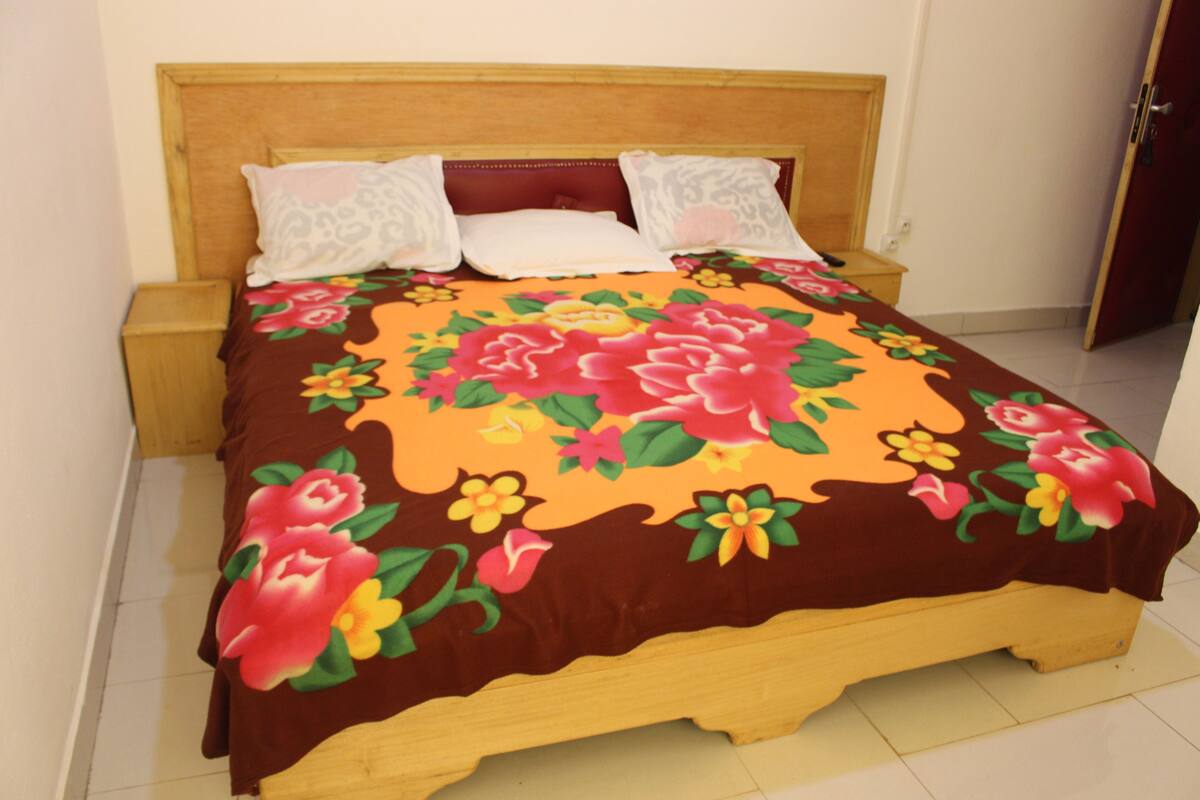 A bed with a floral bedspread, wooden headboard, and two nightstands.