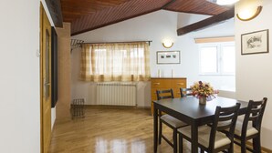 A dining area with a wooden table and chairs, a radiator, and a window with curtains. - Belgrade Center Apartment V (Belgrade)