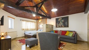 A cozy room with a bed, a grey sofa, a wooden ceiling, and a painting on the wall. - Belgrade Center Apartment V (Belgrade)