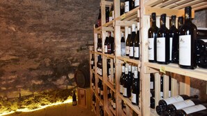 A wine cellar with wooden shelves holding various wine bottles. - Zollersteighof (Albstadt)