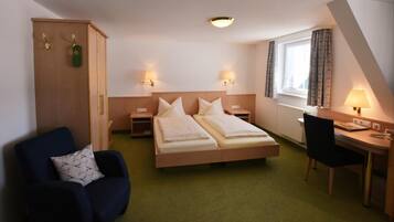 A hotel room with a double bed, a desk with a chair, a wardrobe, and two bedside lamps.