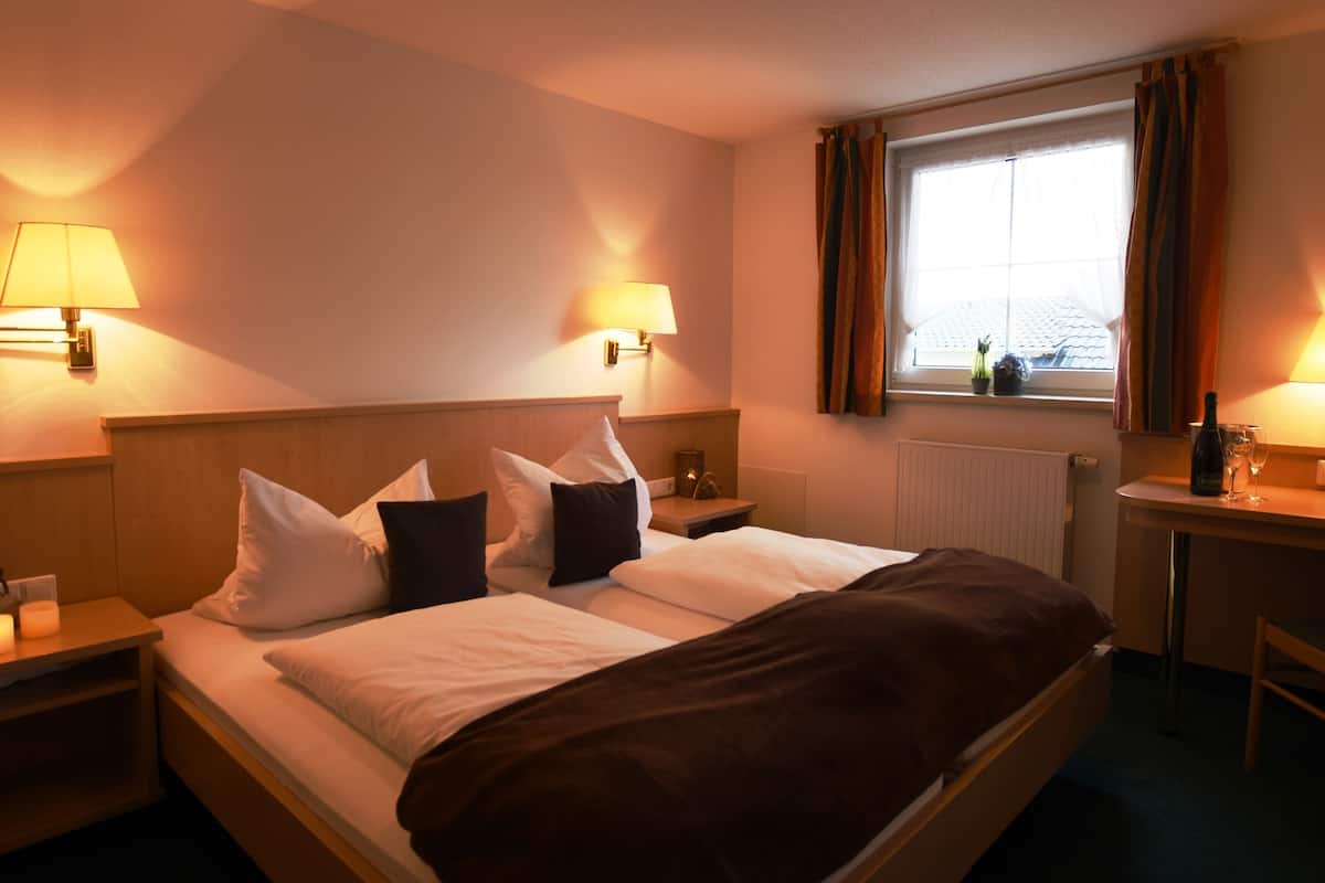 Une chambre d’hôtel comprenant un lit, deux tables de chevet, un bureau et une chaise.